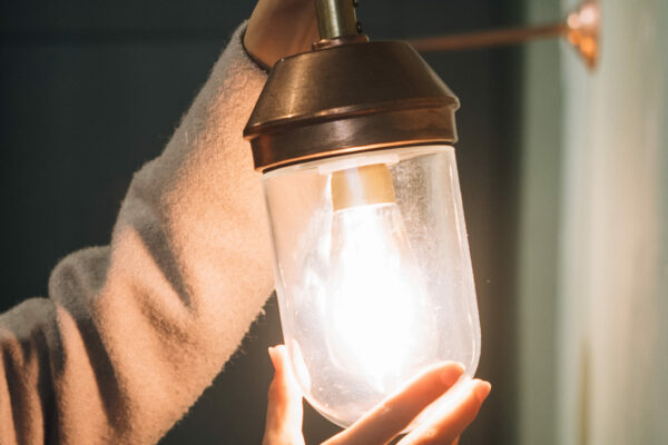Young beautiful woman holds in her hand a small wall lamp, evening